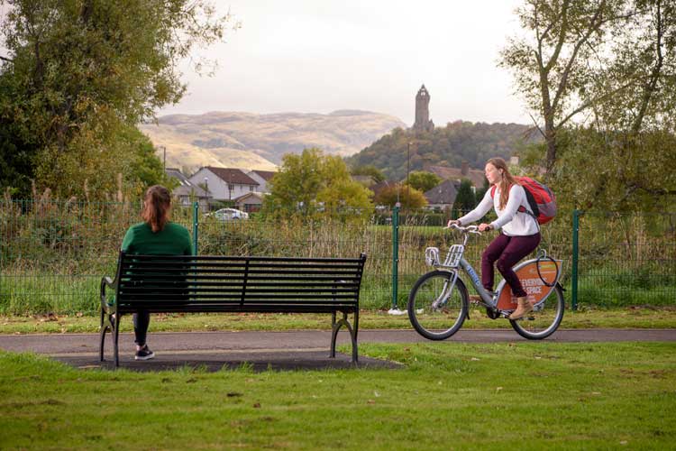 Sustrans Stirling - woman on a bicycle with the Wallace Monument in background