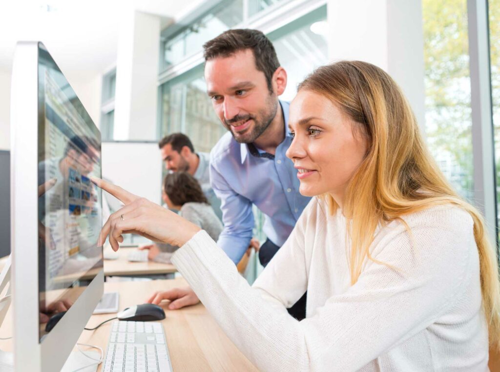 Woman and man operating an iMac